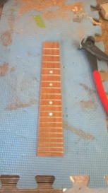 Stage 8: Cut the frets to length and secure them in the fret grooves that were cut earlier. Cut holes for the fret markers and glue them in place.